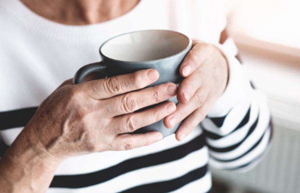 Mains de femme agée tenant une tasse à café